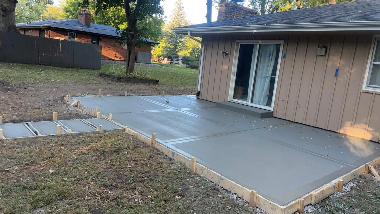 Broom-finish concrete patio wrapping the back of a Northern Illinois home, poured by E.R. Hardscapes with the forms still in place.