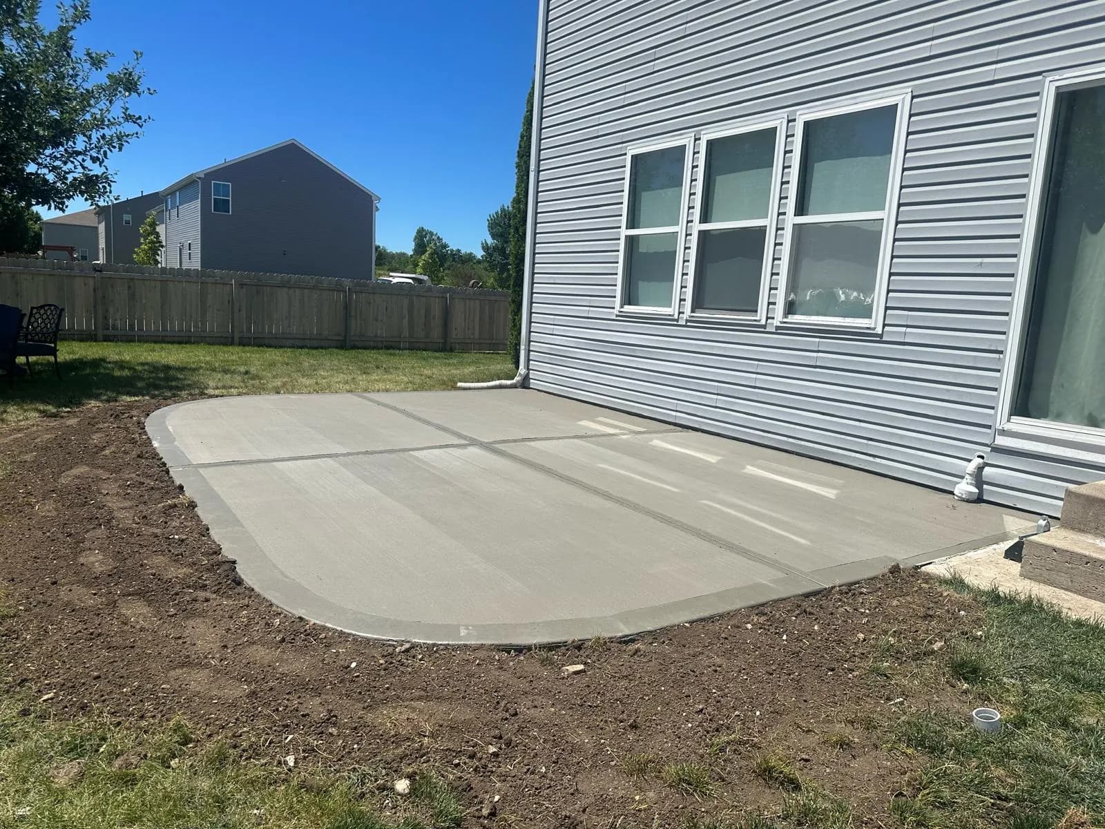 Finished concrete patio with a curved edge and tooled control joints against the back of a Northern Illinois home.