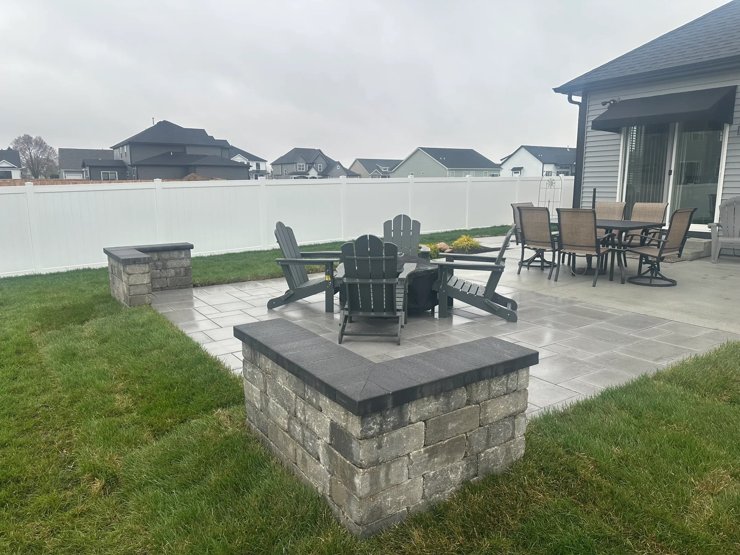 Paver patio with a fire-pit table, Adirondack chairs and stone seat-wall columns built by E.R. Hardscapes.